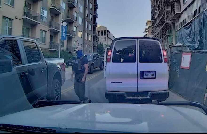 A masked law enforcement officer at a the scene of the arrest