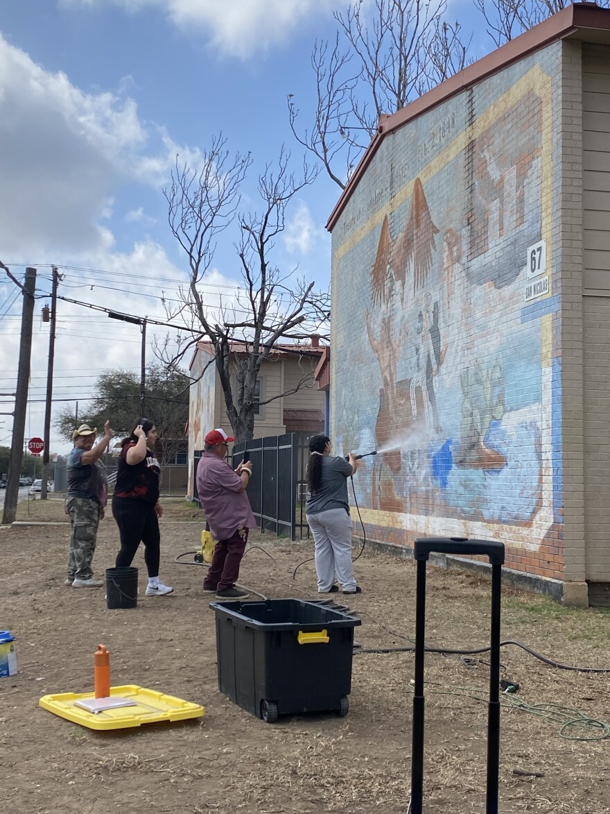Students power washing the wall before applying fresh paint