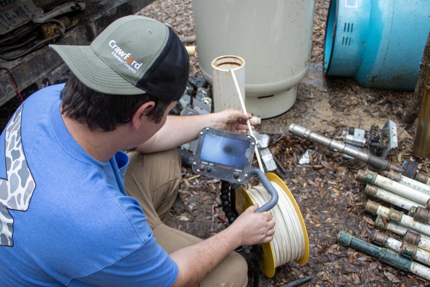 Matthiew Taylor lowers a camera to the bottom of a well in Buda.