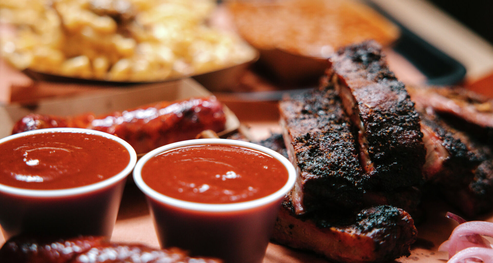 Large servings of barbecue, with pork ribs, sausage, macaroni and cheese, and baked beans.