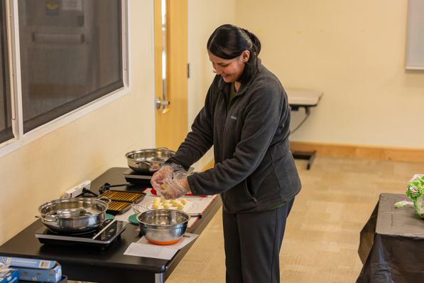 A librarian utilizes several cooking items from the kitchen supply cart to host a teen cooking class.