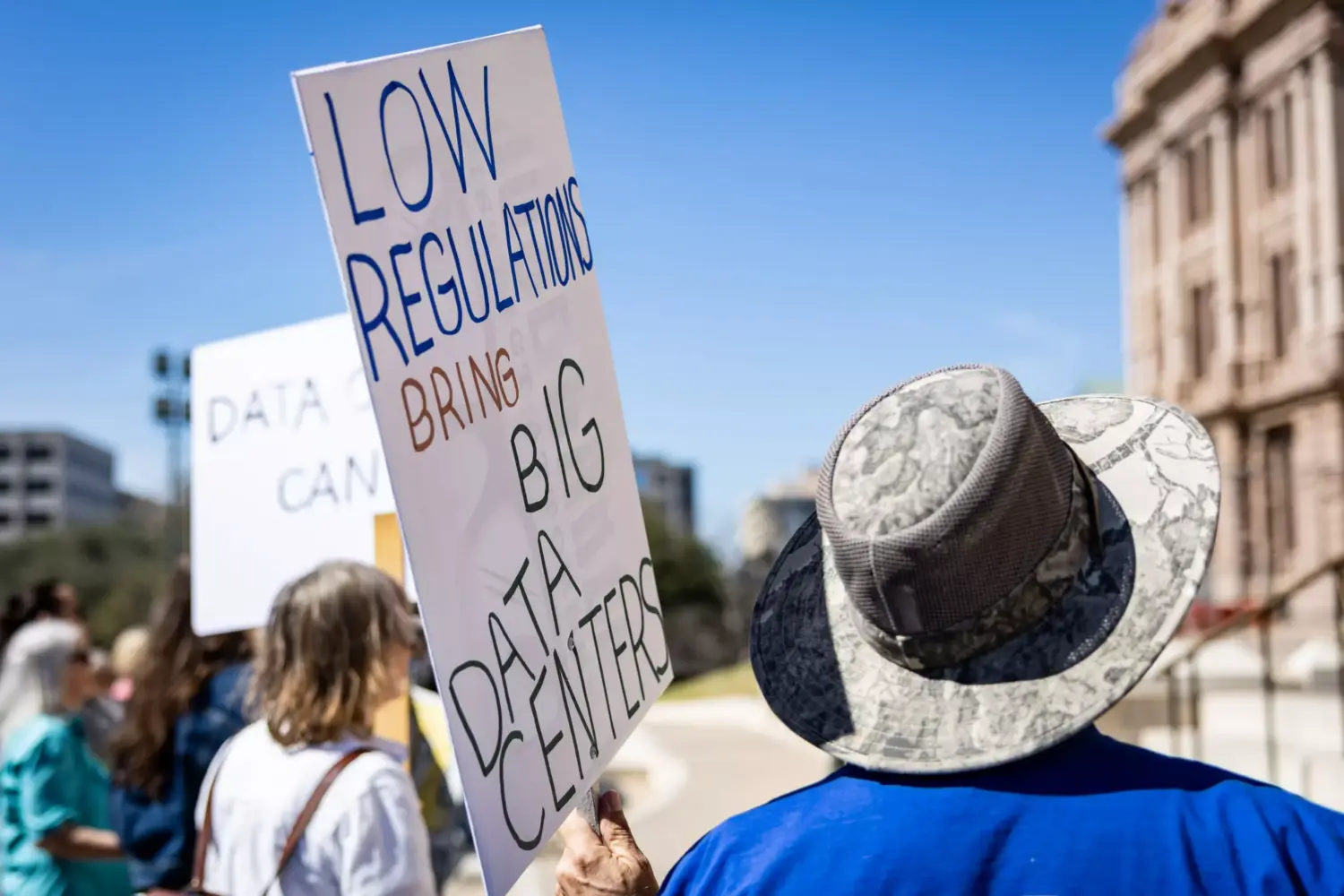 A protestor holds a sign during a rally against the rapid expansion of data centers across Texas on Feb. 23, 2026, at the Texas State Capitol building in Austin.