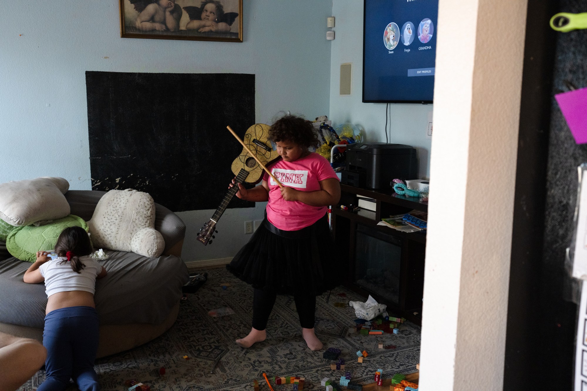 Seven-year-old Freyja Radtke, who suffers from Bardet-Biedl syndrome, a condition which causes excessive weight gain and hormonal imbalances, and in her particular case, an inability to control her own appetite, pretends to play the violin with a guitar at the family’s home on Saturday, February 28, 2026 in El Paso, Texas. Because Freyja is due for a medical test next week, she is forced to be off of Imcivree, the medication that controls her hormonal imbalances that lead to excessive hunger, until after the test.