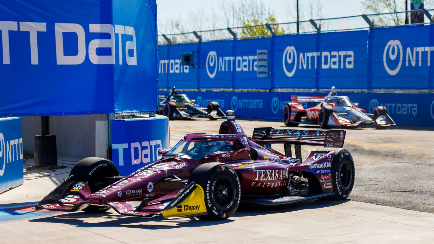 Texas A&M branded maroon IndyCar driving down the track with the other cars