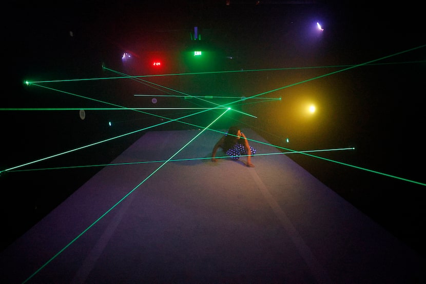 A visitor makes her way through the laser maze vault heist interactive feature at MoMoney:...