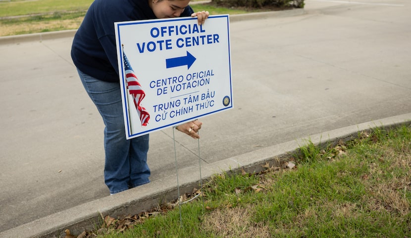 Poll worker Lidia Pedraza places an “Official Vote Center” sign outside of the Pleasant...