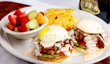 A plate with fried eggs, fruit and other breakfast foods.