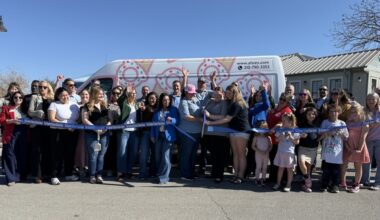 A ribbon being cut in front of an ice cream truck.