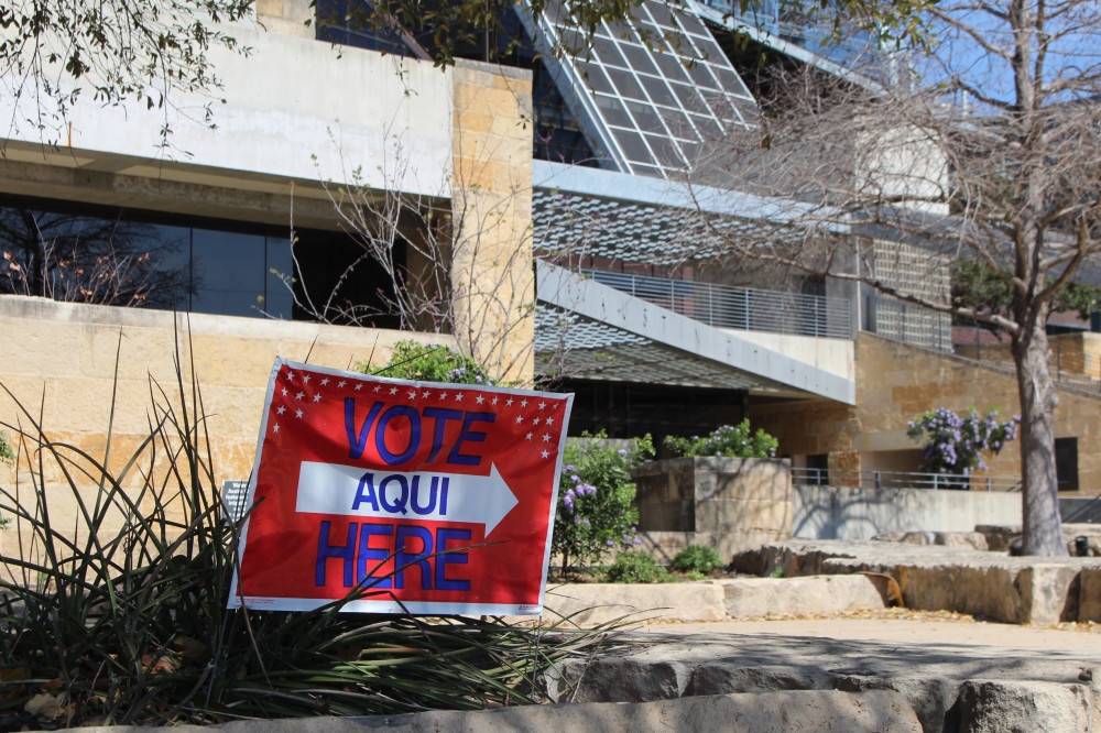 A sign says "vote here" in front of a polling place