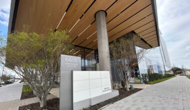 Exterior of a high rise office building and freestanding monument sign featuring The Tower at Hall Park lettering.
