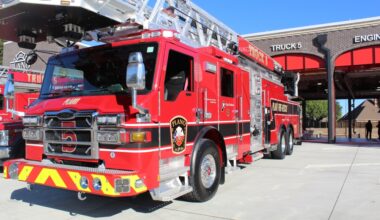 A firetruck parked outside the bay of a brick fire station