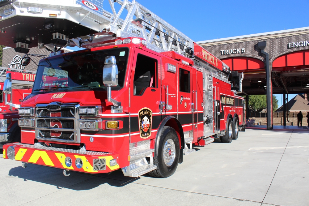 A firetruck parked outside the bay of a brick fire station