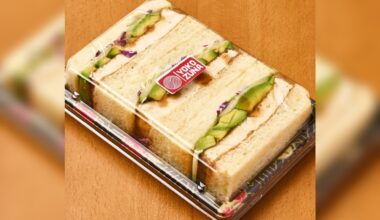 A sandwich cut into three equal part and packaged in a to-go container with a clear lid