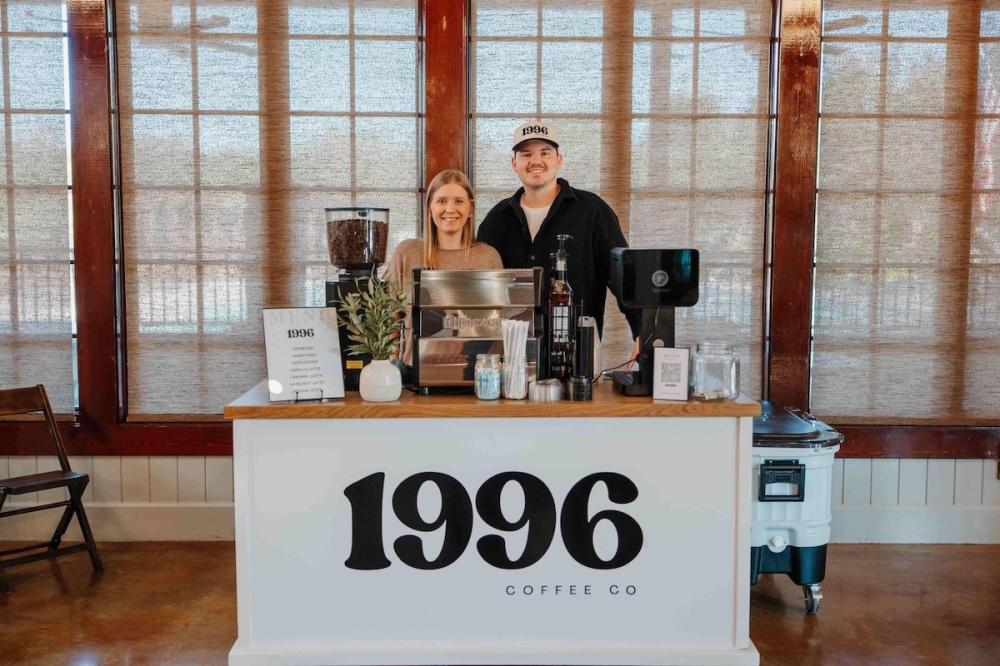 The owners of the coffee service stand behind the counter of the coffee cart.