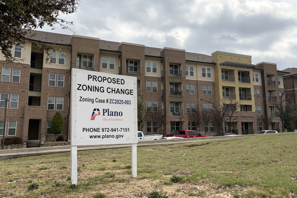 A sign with information about a proposed zoning change in front of an apartment building