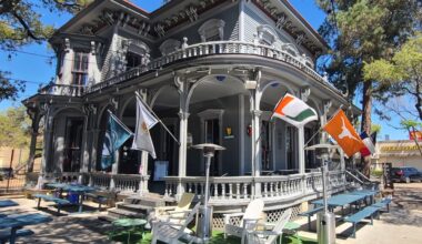 The outside of a historic Victorian home with decorative flags for sports teams