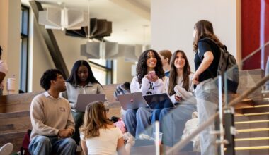 a group of students work on laptops in a common space