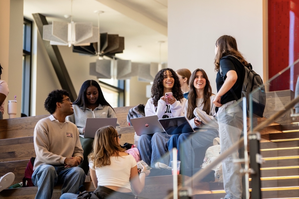 a group of students work on laptops in a common space