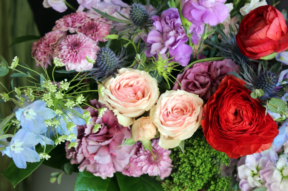Flower arrangement featuring purple, pink, blue and red flowers.