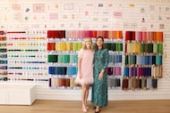 Two women standing in front of needlepoint designs and colorful threads
