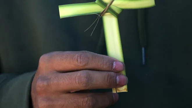 A St. Pius X parishioner fashioned a cross from a palm frond during a past Palm Sunday.