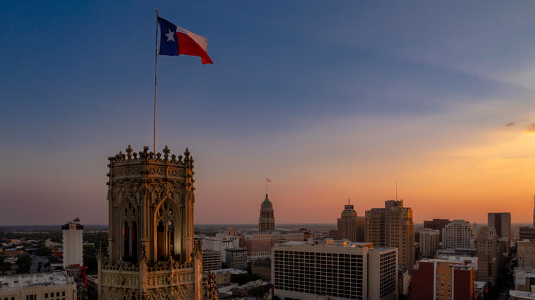 Texas flag blowing in wind atop downtown building