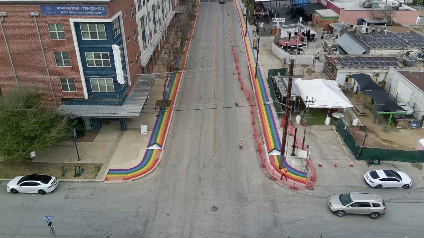 An aerial view of a street in San Antonio, Texas, where the sidewalks are painted with rainbow stripes