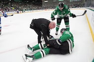 Dallas Stars center Roope Hintz, bottom right, is checked by a trainer as defenseman Miro...