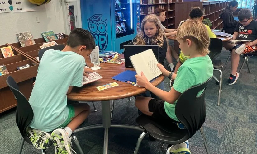 Third grade students Brady Jackson, Everly Collier and Finn Fratila read books in the Windsor Park Elementary library. (Lauren Wagner)