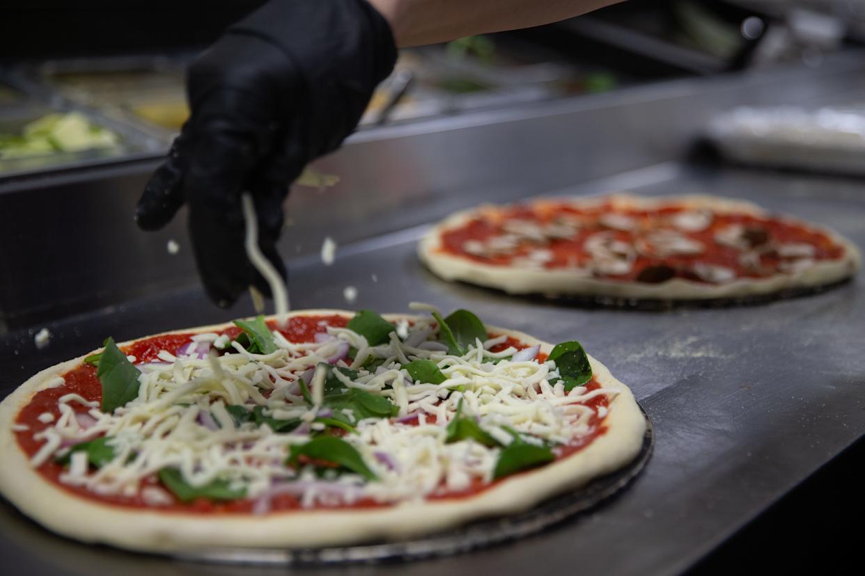 Pam Chavez, owner of Saucy Mama's, sprinkles mozzarella cheese on pizzas at the restaurant in Corpus Christi on Jan. 9.