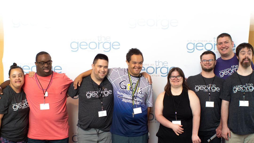 A group of people standing in front of a red carpet sign reading
