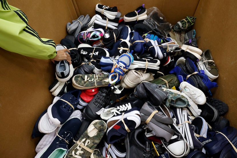 Catherine Bates of Dallas, a volunteer for Buckner Shoes for Orphan Souls program, sorts the...