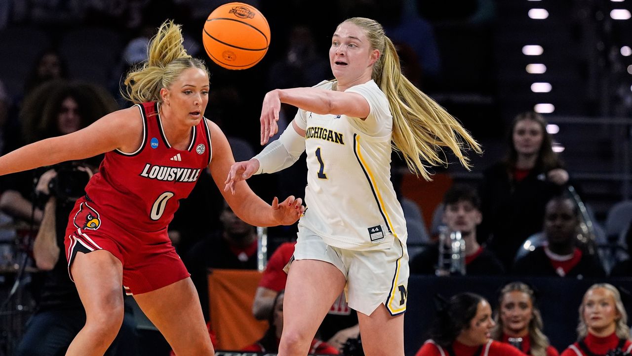 Michigan guard Olivia Olson (1) makes a pass under pressure from Louisville forward Laura Ziegler (0) in the first half in the Sweet 16 of the NCAA college basketball tournament, Saturday, March 28, 2026, in Fort Worth, Texas. (AP Photo/Tony Gutierrez)