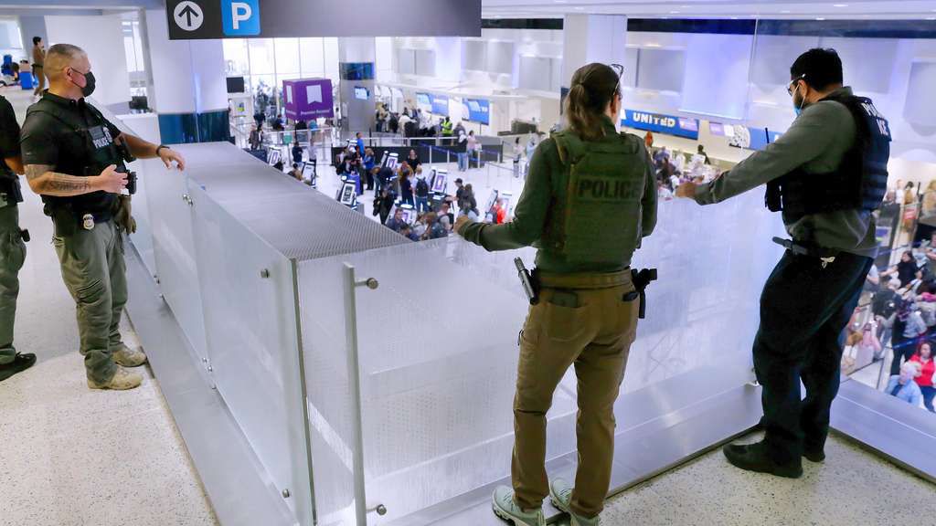 Federal immigration agents peer over railings on the floor above the lines of air travelers progressing to the TSA security checkpoint in Terminal C at the George Bush Intercontinental Airport, Monday, March 23, 2026, in Houston. (AP Photo/Michael Wyke)