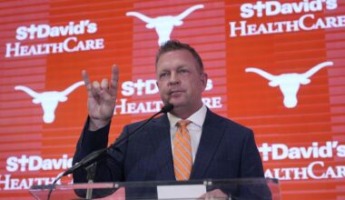 Jim Schlossnagle flashes a hook'em sign as he speaks at a news conference after he was introduced as the new NCAA college head baseball coach at Texas, Wednesday, June 26, 2024, in Austin, Texas. Schlossnagle left rival program Texas A&M. (AP Photo/Eric Gay)