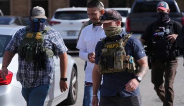 Federal agents escort a man to a transport bus after he was detained following an appearance at immigration court, on July 22, 2025, in San Antonio.