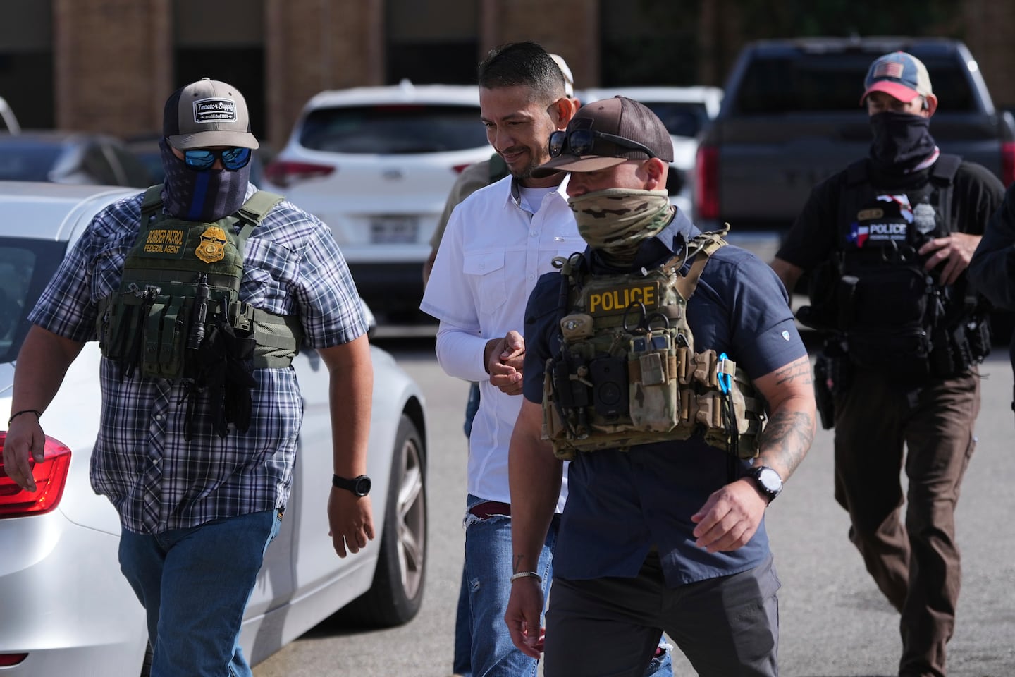 Federal agents escort a man to a transport bus after he was detained following an appearance at immigration court, on July 22, 2025, in San Antonio.