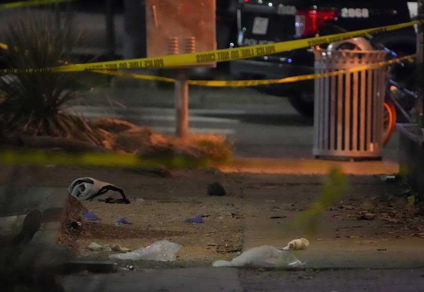 Debris litters the sidewalk at the scene on West Sixth Street after a shooting outside...