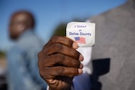 A Dallas County voter holds up his “I voted in Dallas County” sticker outside of the...