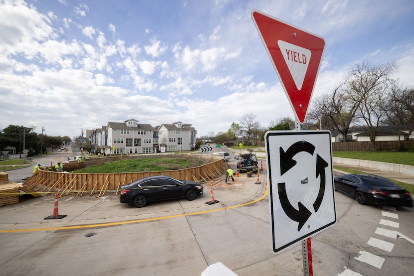 A road sign announces the roundabout in Oak Cliff at N Polk St & N Tyler St as a wall is...