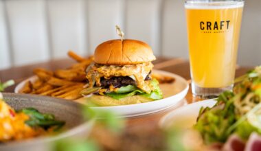 A large burger oozing with cheese and a beer.