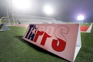 A TAPPS sign is on the field backlit from stadium lights in the fog. Ursuline defeated John...