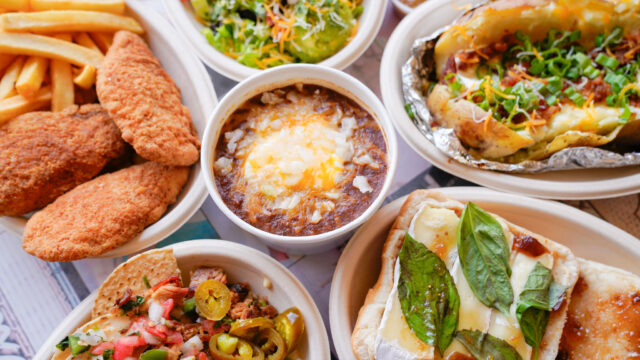 Various foods such as fried chicken, soup, and sandwiches arranged in a circle on a table.