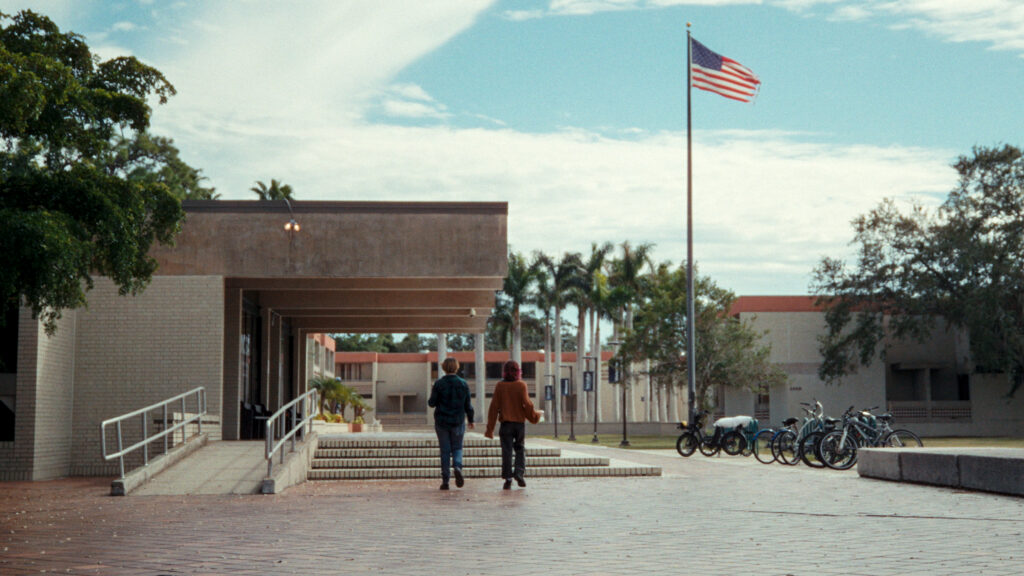Two people walk on a college campus in a still image from the film 
