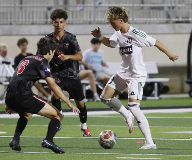 Southlake Carroll’s Cole Swett kicks the ball between Mansfield Legacy midfielders Zavier Green and Luke Lenamond during the first half of a UIL bi-district round soccer playoff game at Crowley ISD Multi-Purpose Stadium in Fort Worth, Texas, on Friday, March 20, 2026.
