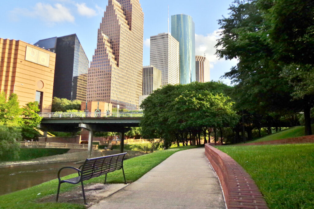 Image shows a bench and the skyline in the background in Houston.