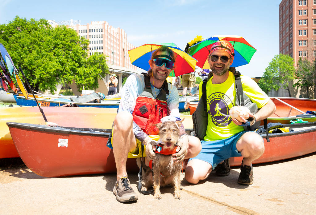 Image shows two participants in the Buffalo Bayou Partnership Regatta in Houston posing with their boat and dog.