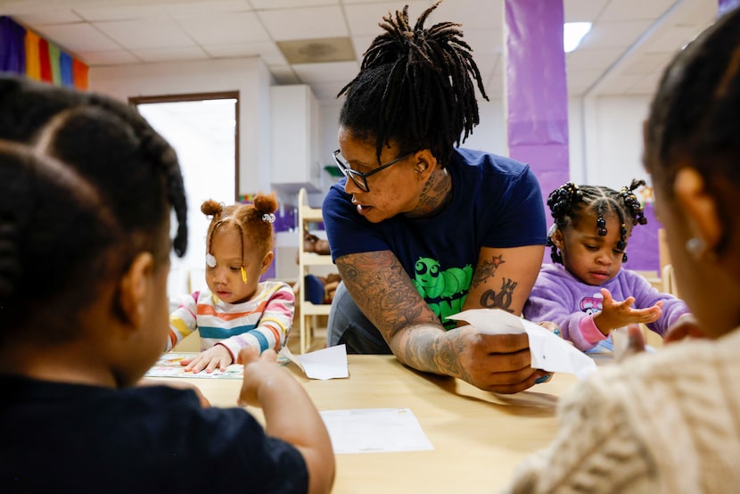 Carla Wright (center) helps her students work through a sticker worksheet at Journeys Child...
