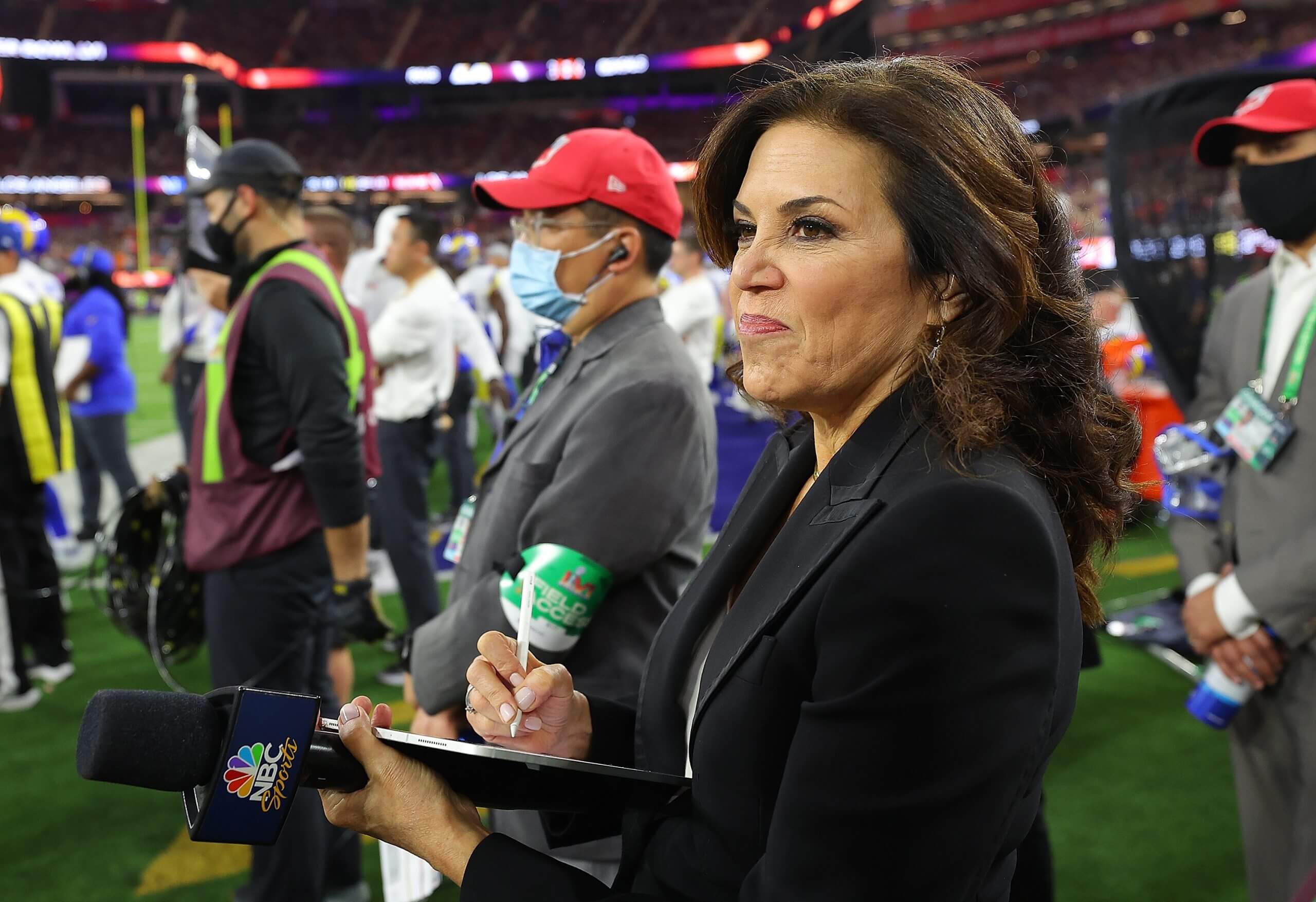 Commentator Michele Tafoya watches and takes notes while holding a microphone on the sideline during Super Bowl LVI at SoFi Stadium.