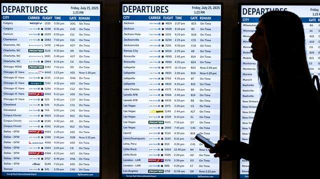 A woman walks past various screens displaying flight information at George Bush Intercontinental Airport in Houston, Texas.